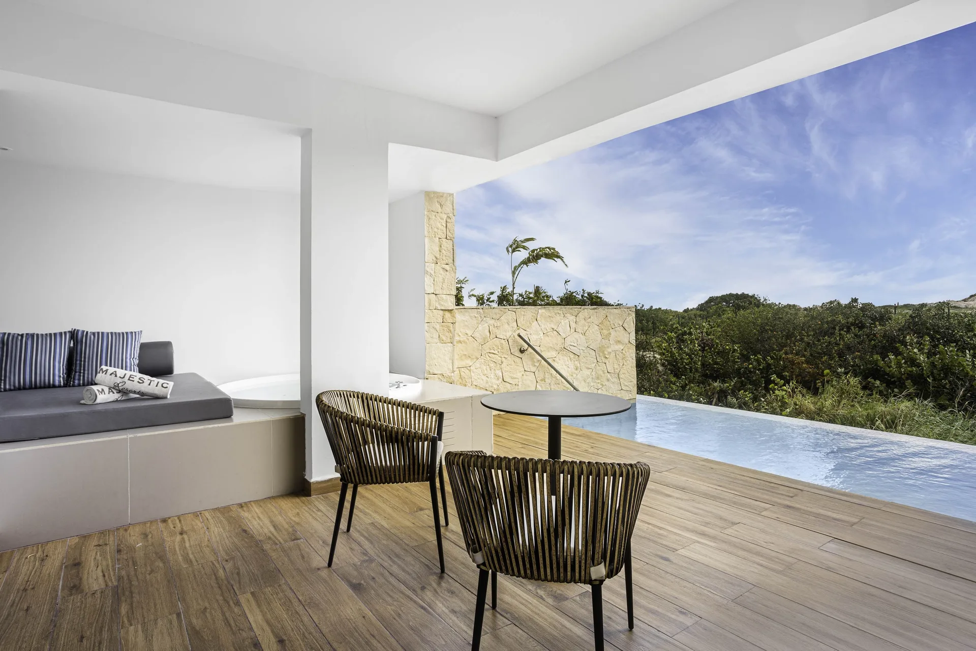 Covered swim-up suite terrace facing greenery at Majestic Elegance Costa Mujeres.