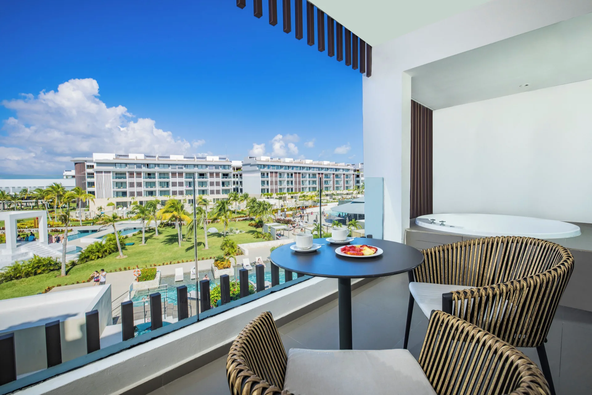 Junior Suite balcony at Majestic Elegance Costa Mujeres with outdoor jacuzzi, table, chairs, and resort view.