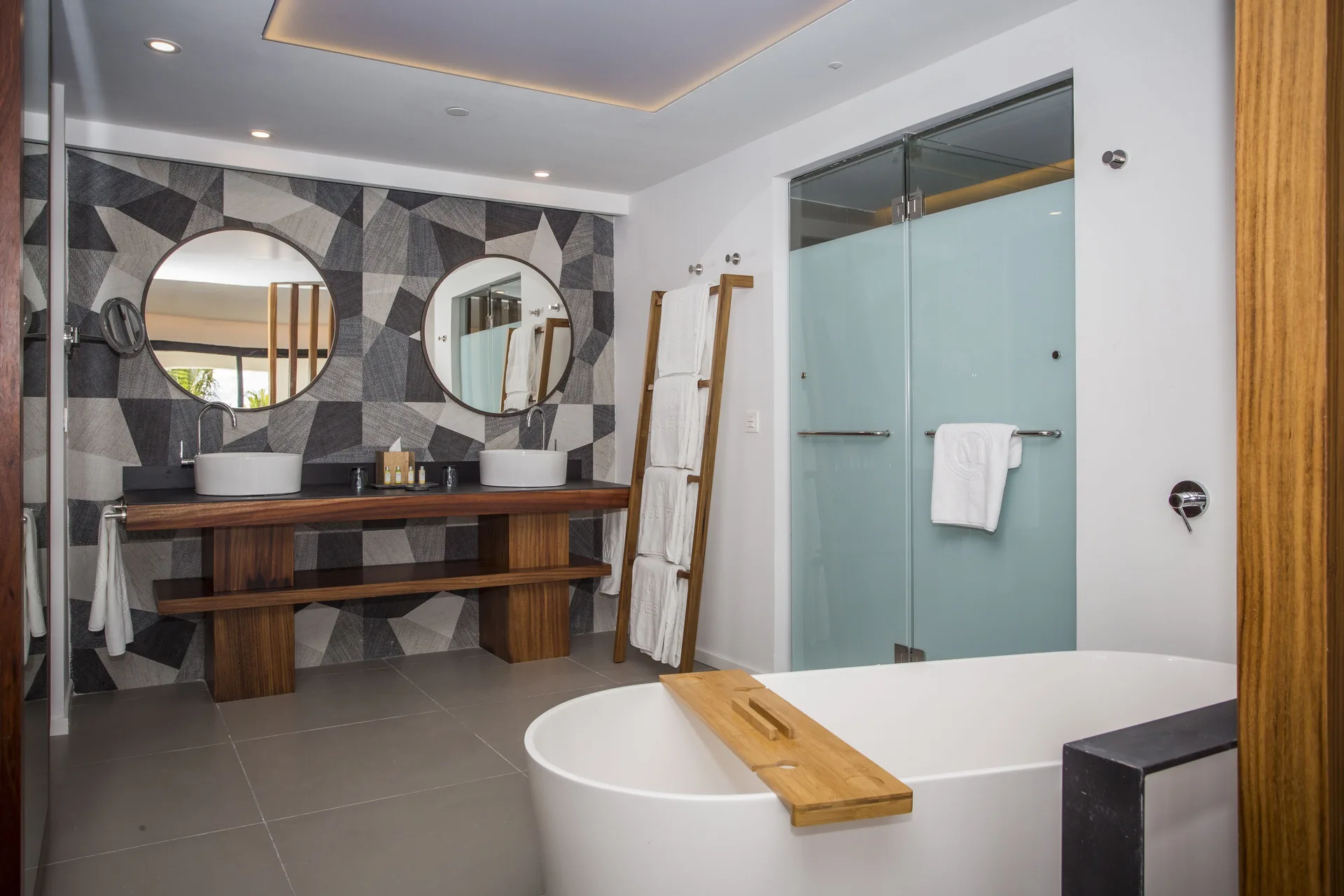 Swim Up Suite bathroom at Majestic Elegance Costa Mujeres with tub, double vanity, and glass shower.