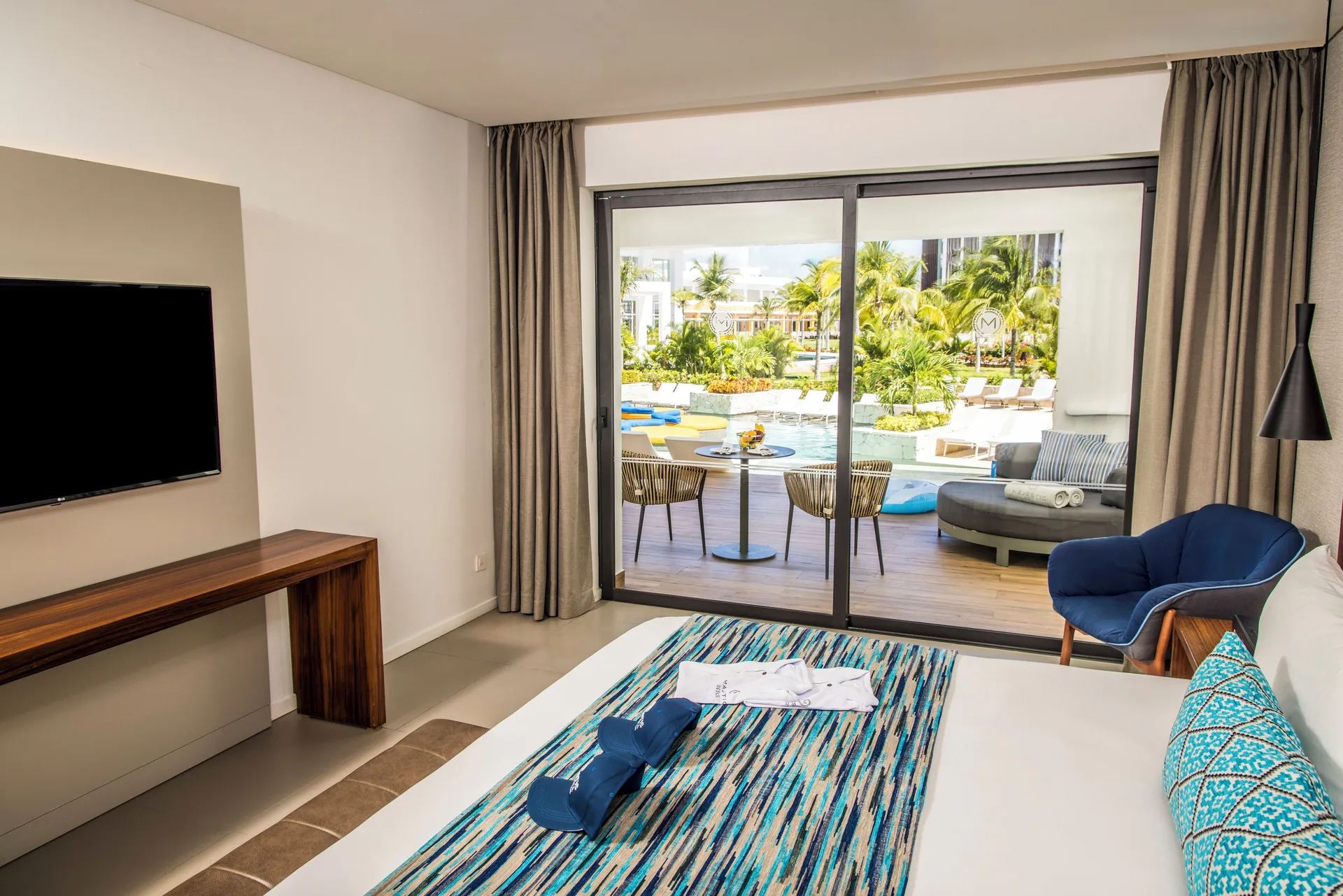 Swim Up Suite bedroom and terrace at Majestic Elegance Costa Mujeres with lounge seating outside.
