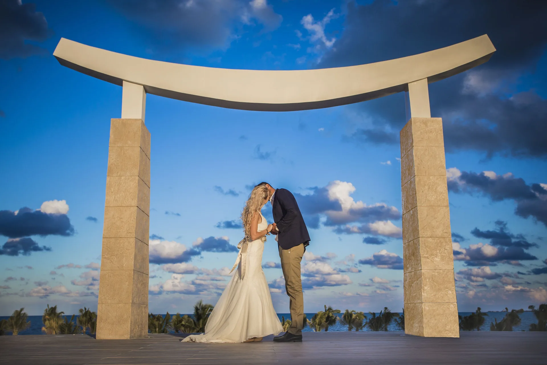 Wedding couple beneath a seaside ceremony arch at Majestic Elegance Costa Mujeres.