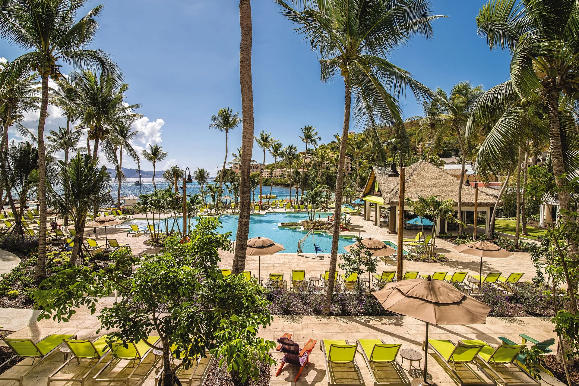 Palm-framed pool deck and beach at Margaritaville Vacation Club - St. Thomas.