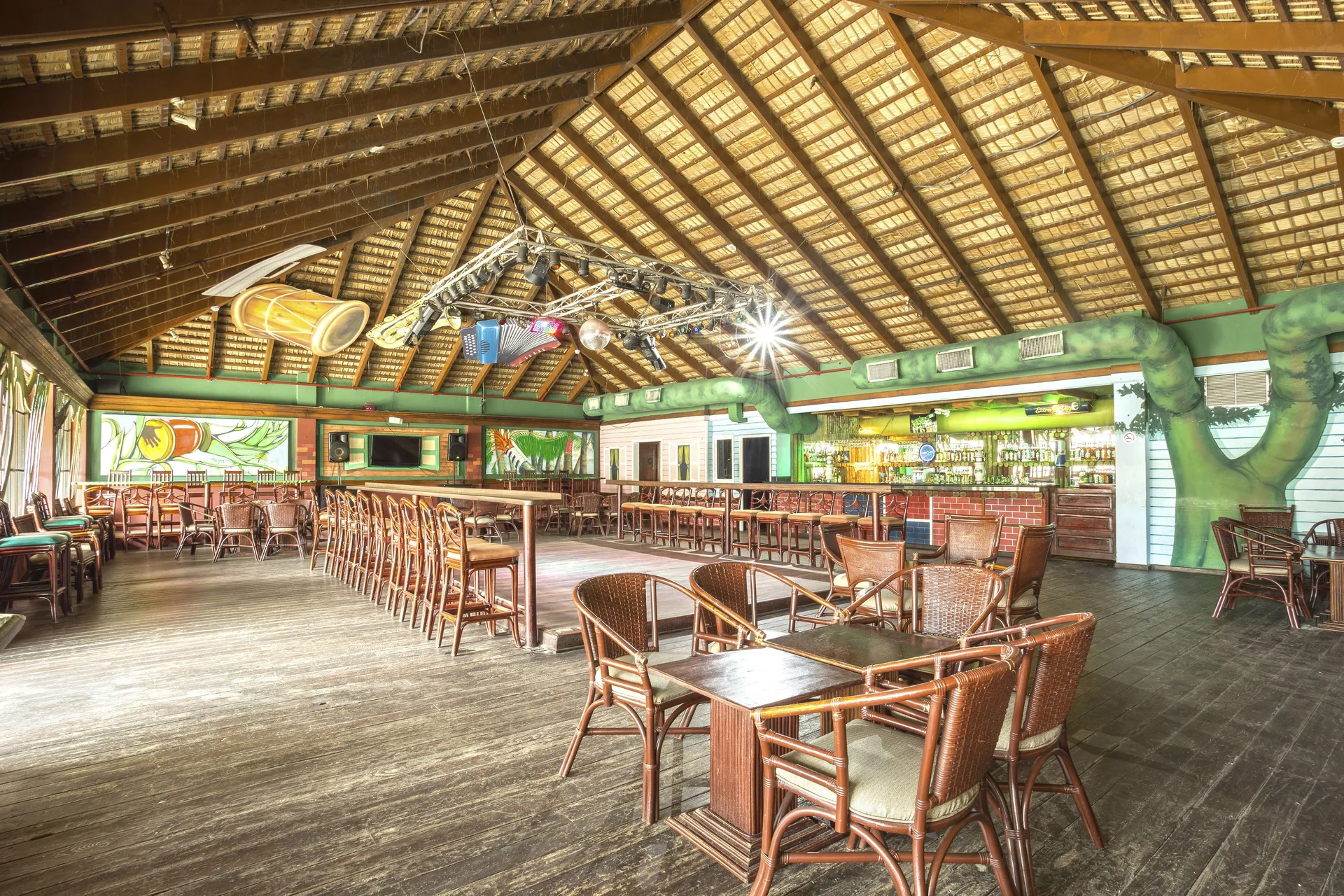Dance bar with wicker seating, high bar chairs, and stage lighting at Marien Puerto Plata.