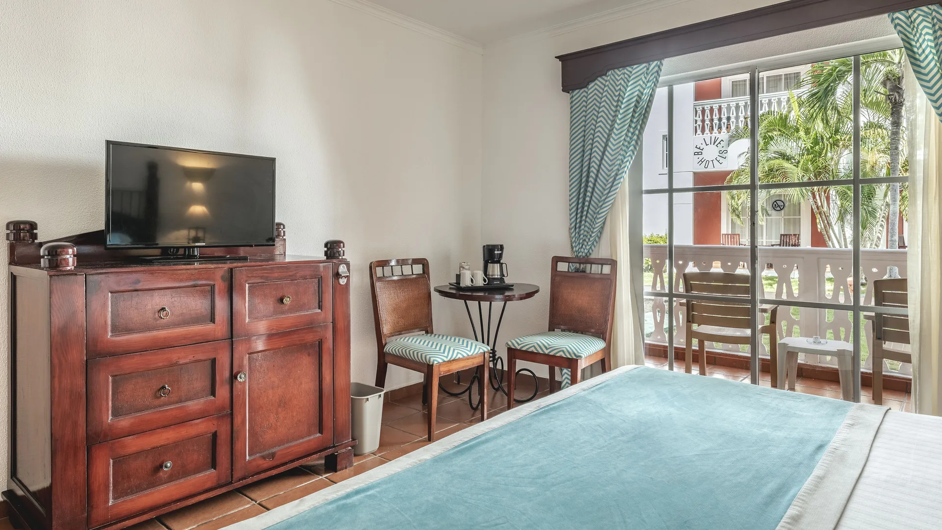 Deluxe Room Garden View dresser, TV, table, and balcony at Marien Puerto Plata.