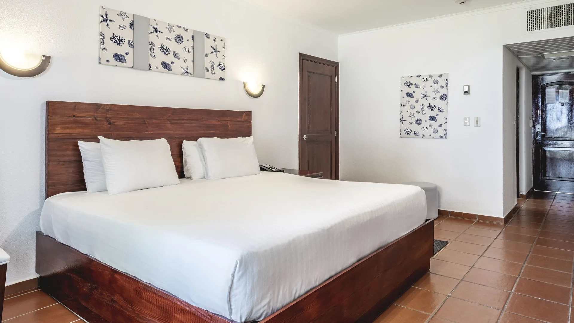 Deluxe Ocean View king room with hallway, tiled floor, and shell artwork at Marien Puerto Plata.