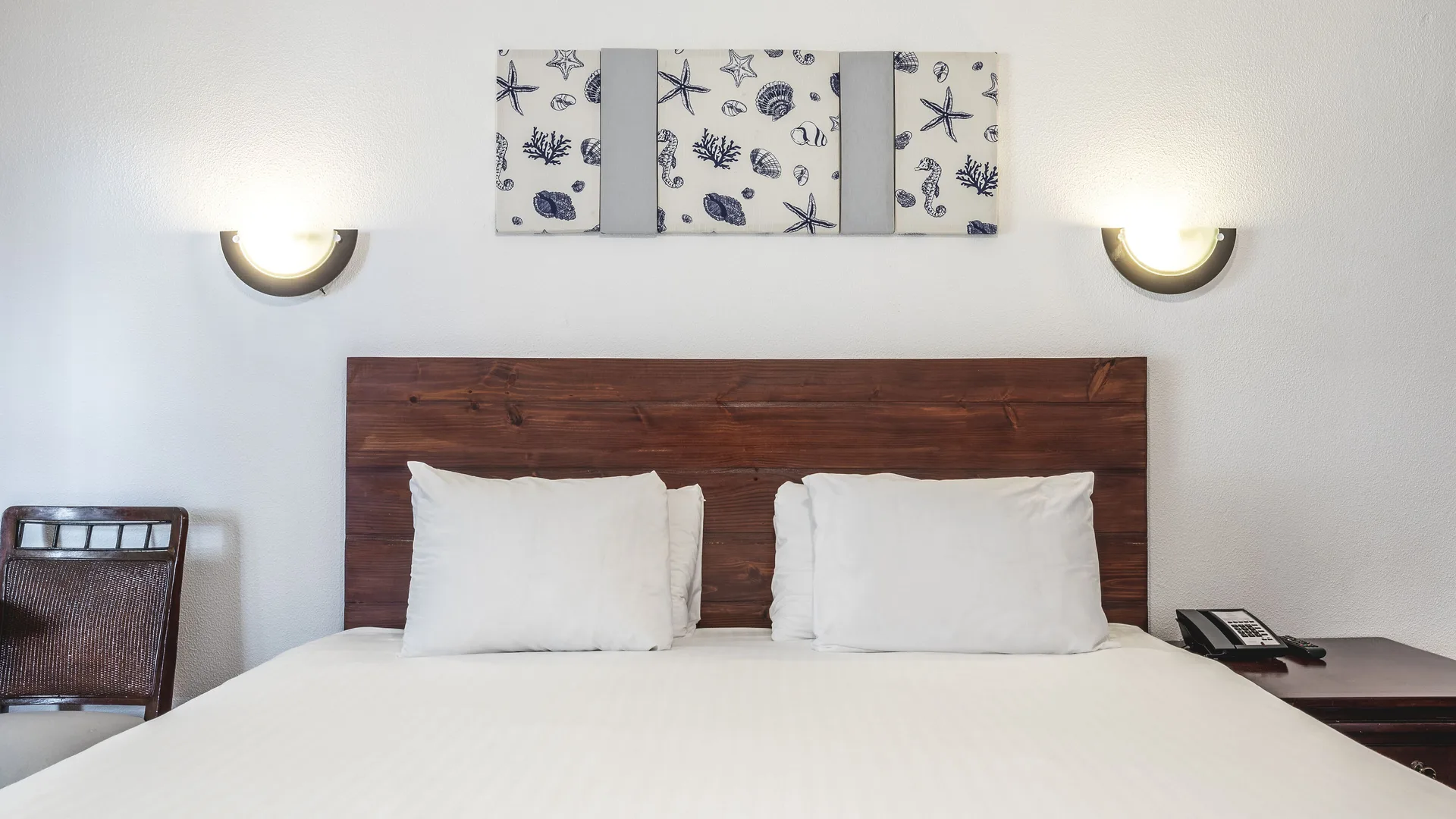 King bed headboard with shell artwork and wall sconces at Marien Puerto Plata.