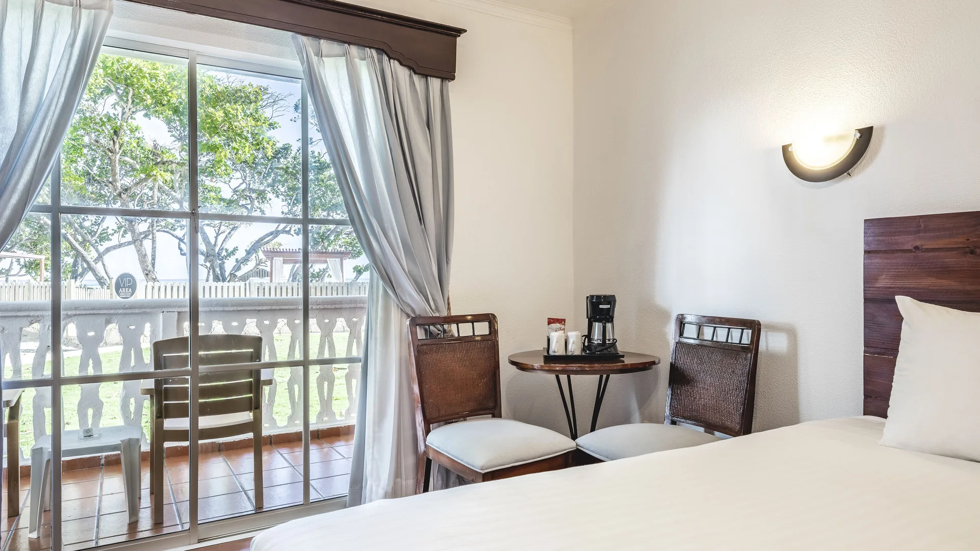 Balcony doors and coffee table beside the king bed in a Deluxe Ocean View room at Marien Puerto Plata.