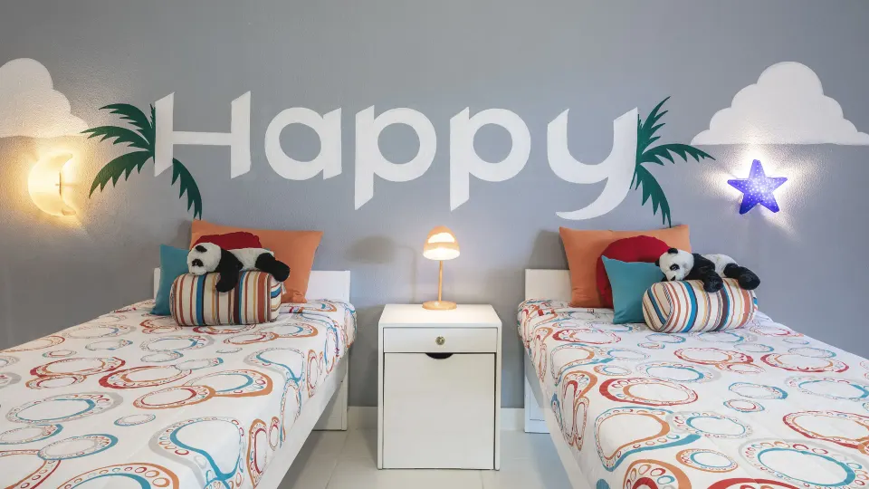 Kids' bedroom with two twin beds, panda toys, and a Happy wall mural at Marien Puerto Plata.
