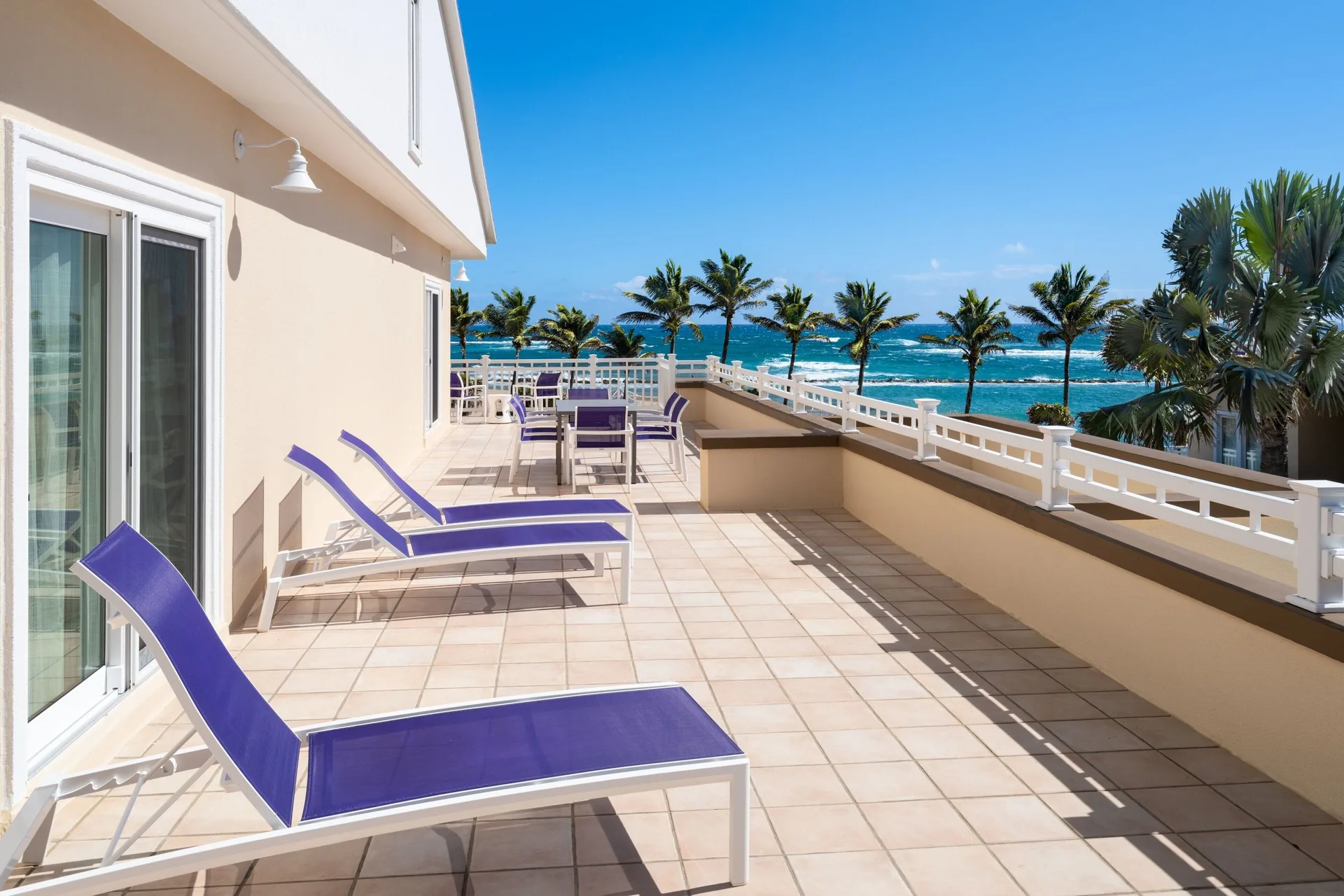 Oceanfront balcony of a three-bedroom villa at Marriott's St. Kitts Beach Club with loungers and table.
