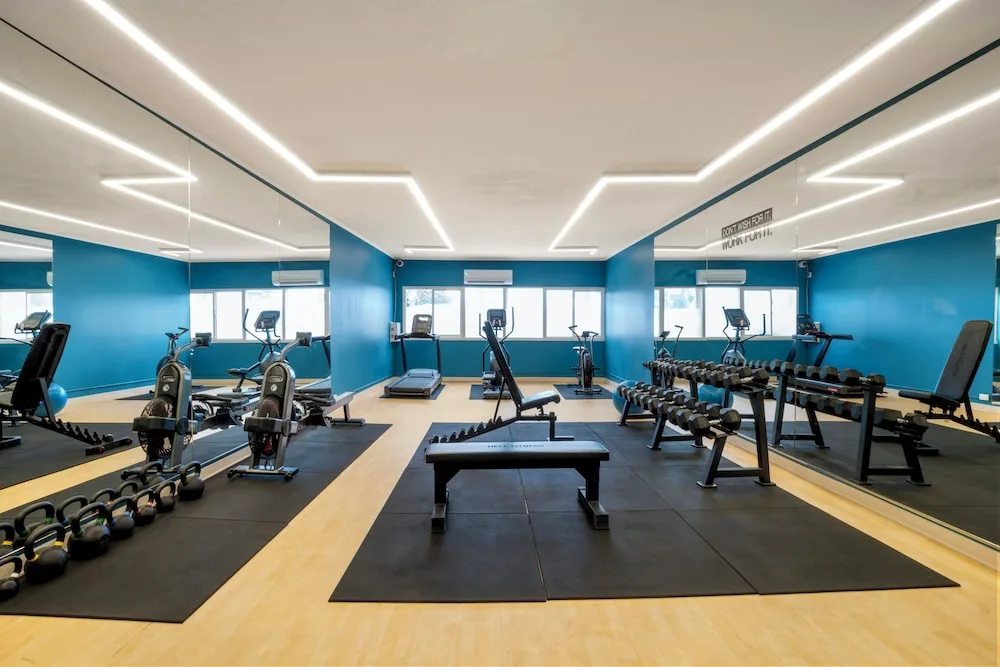 Bright fitness center with mirrors, weights and cardio equipment at Maui Beach Hotel.