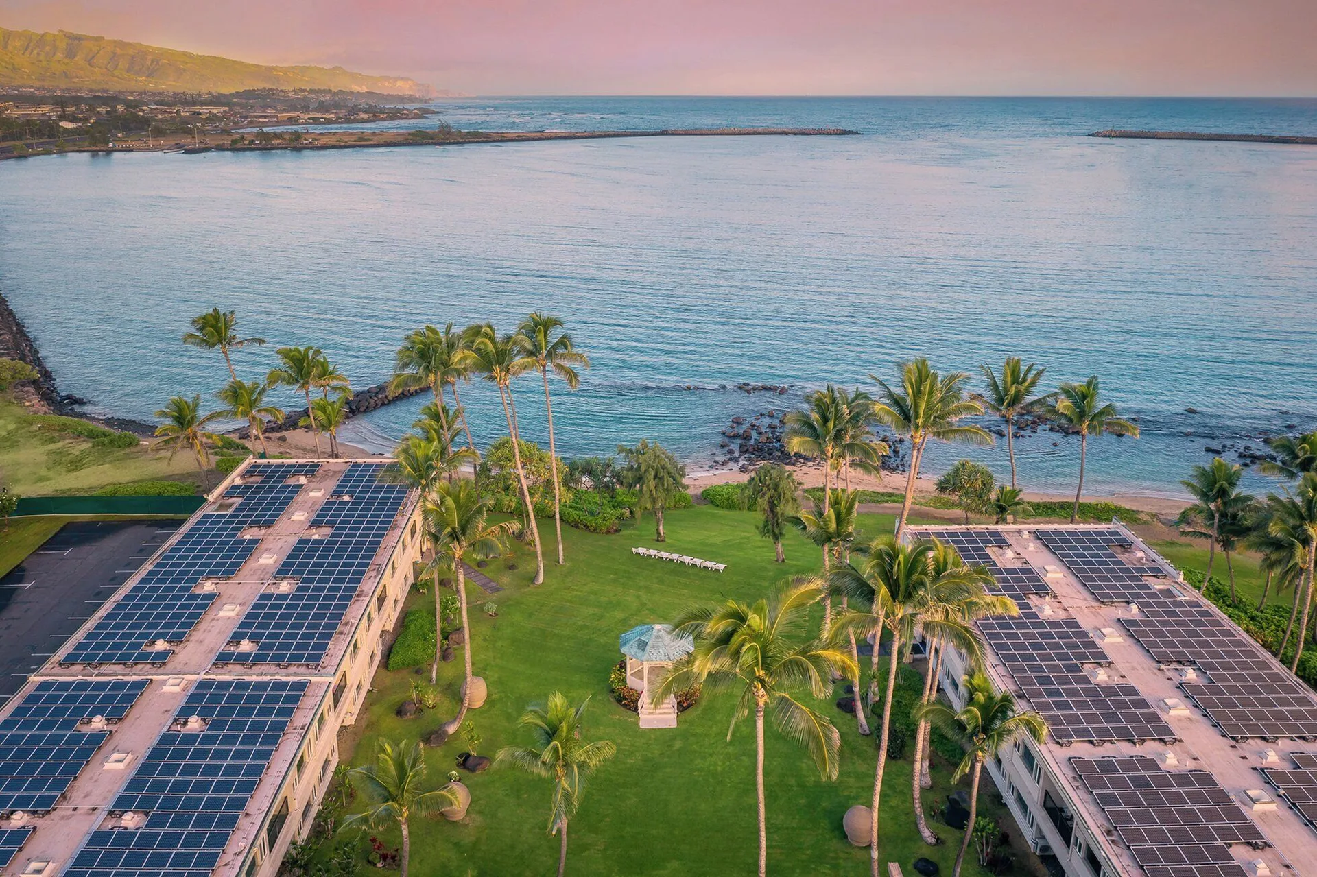 Overhead view of Maui Beach Hotel lawns, palms, rooftops, and ocean bay.