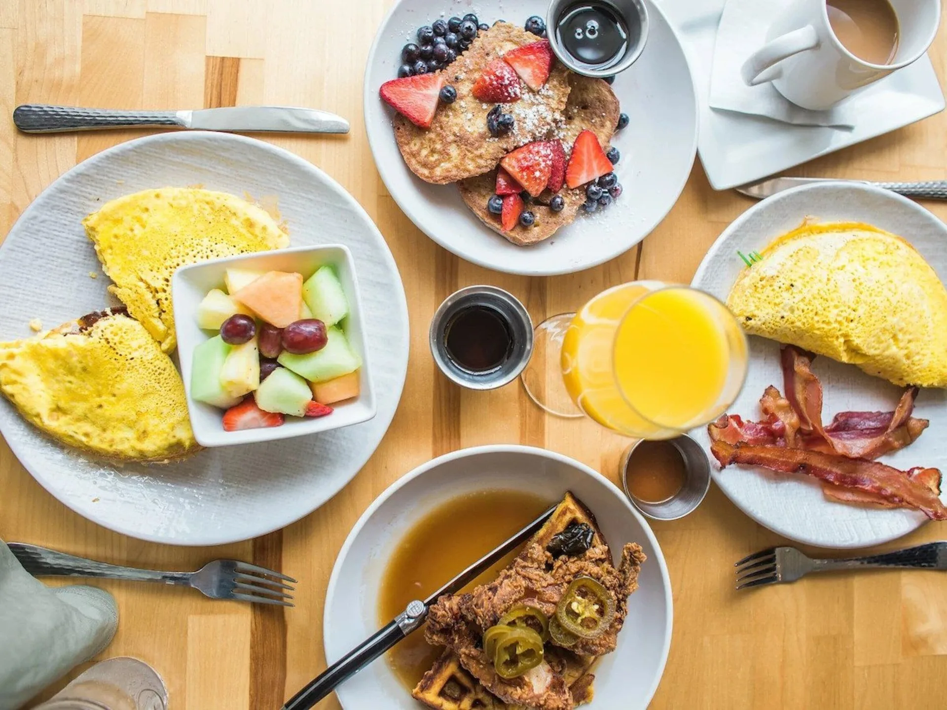 Breakfast plates with omelets, fruit, French toast, waffles, bacon, and juice at Maui Beach Hotel.