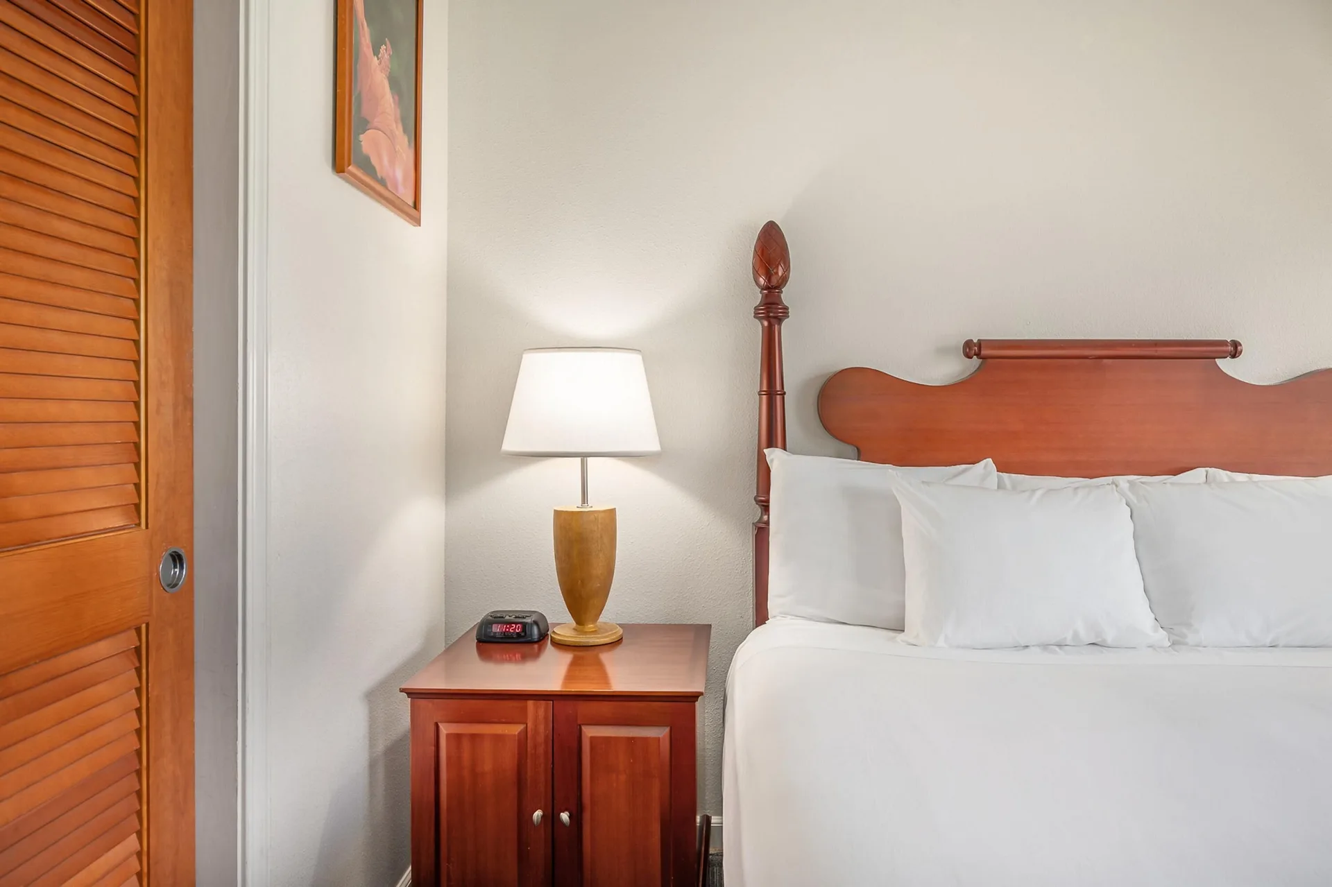 Standard Room One Bed at Maui Beach Hotel with bed, wood headboard, bedside lamp, clock, and closet door.