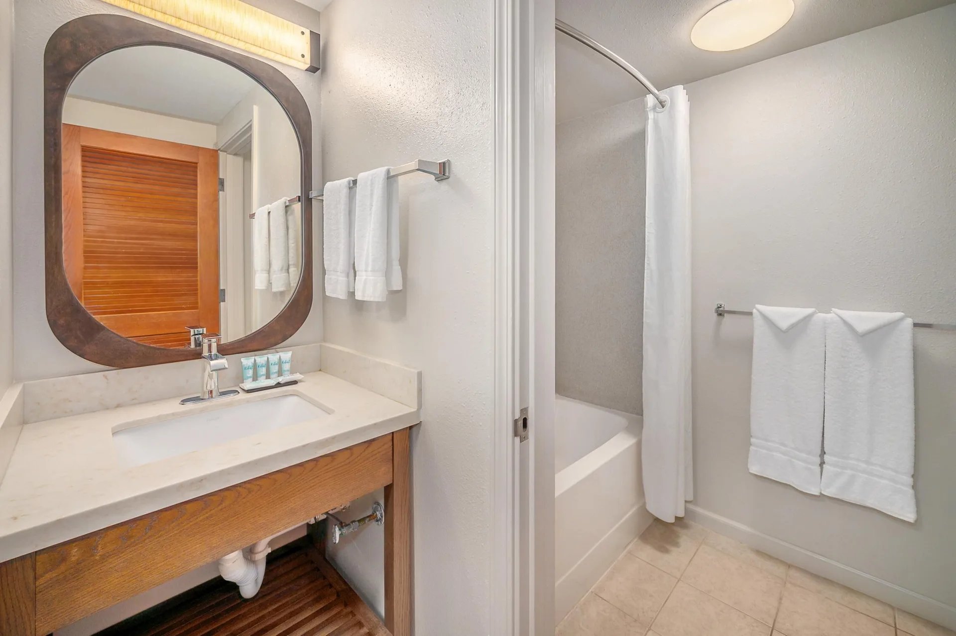 Standard Room bathroom vanity, mirror, towels, and tub at Maui Beach Hotel.