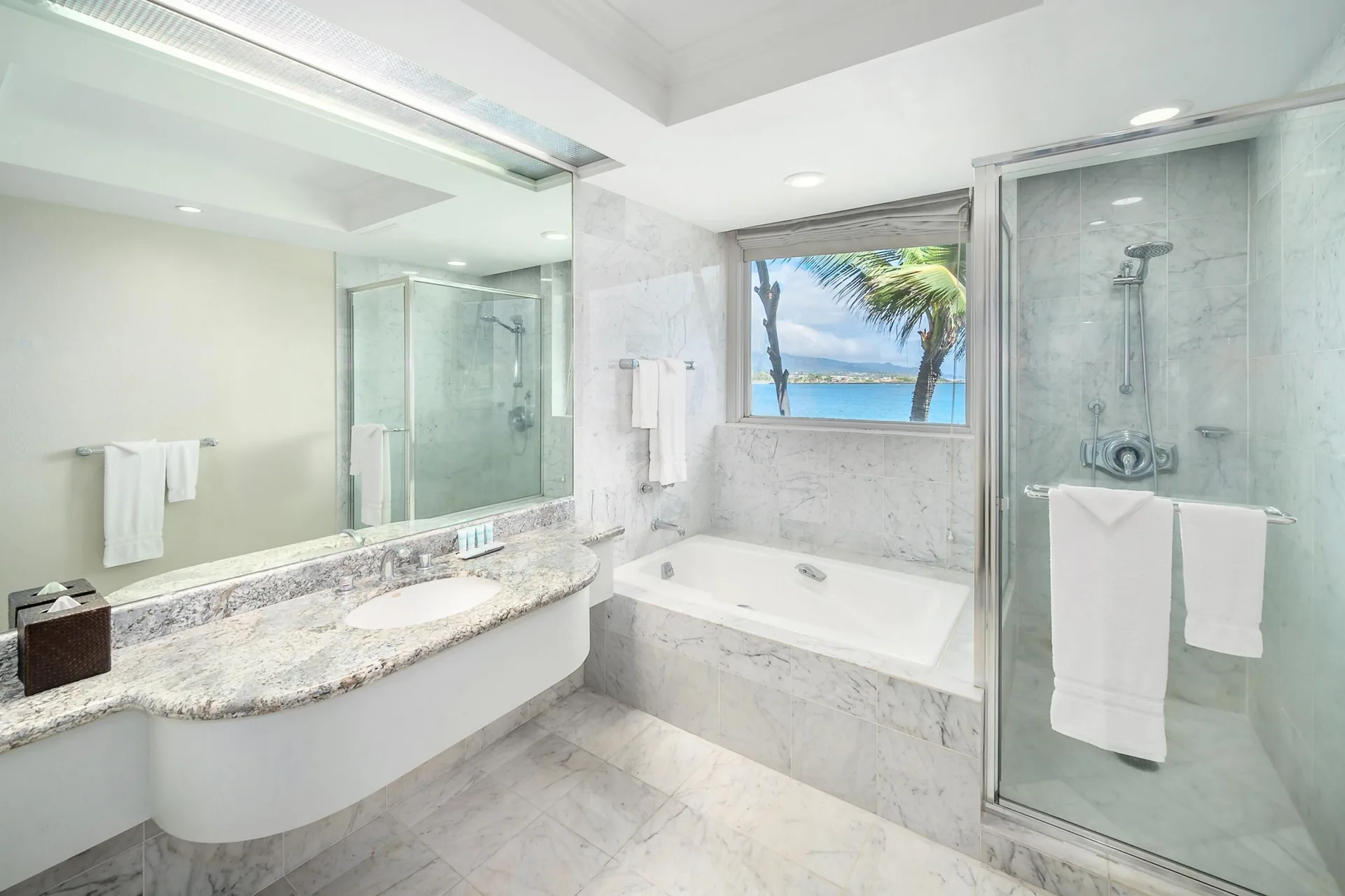 Oceanfront suite bathroom vanity, tub, shower, and ocean-facing window at Maui Beach Hotel.