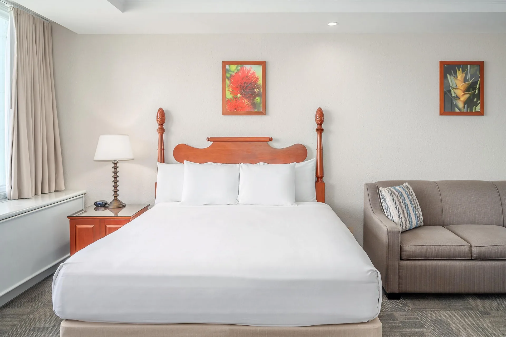 Oceanfront suite king bed with sofa and tropical wall art at Maui Beach Hotel.