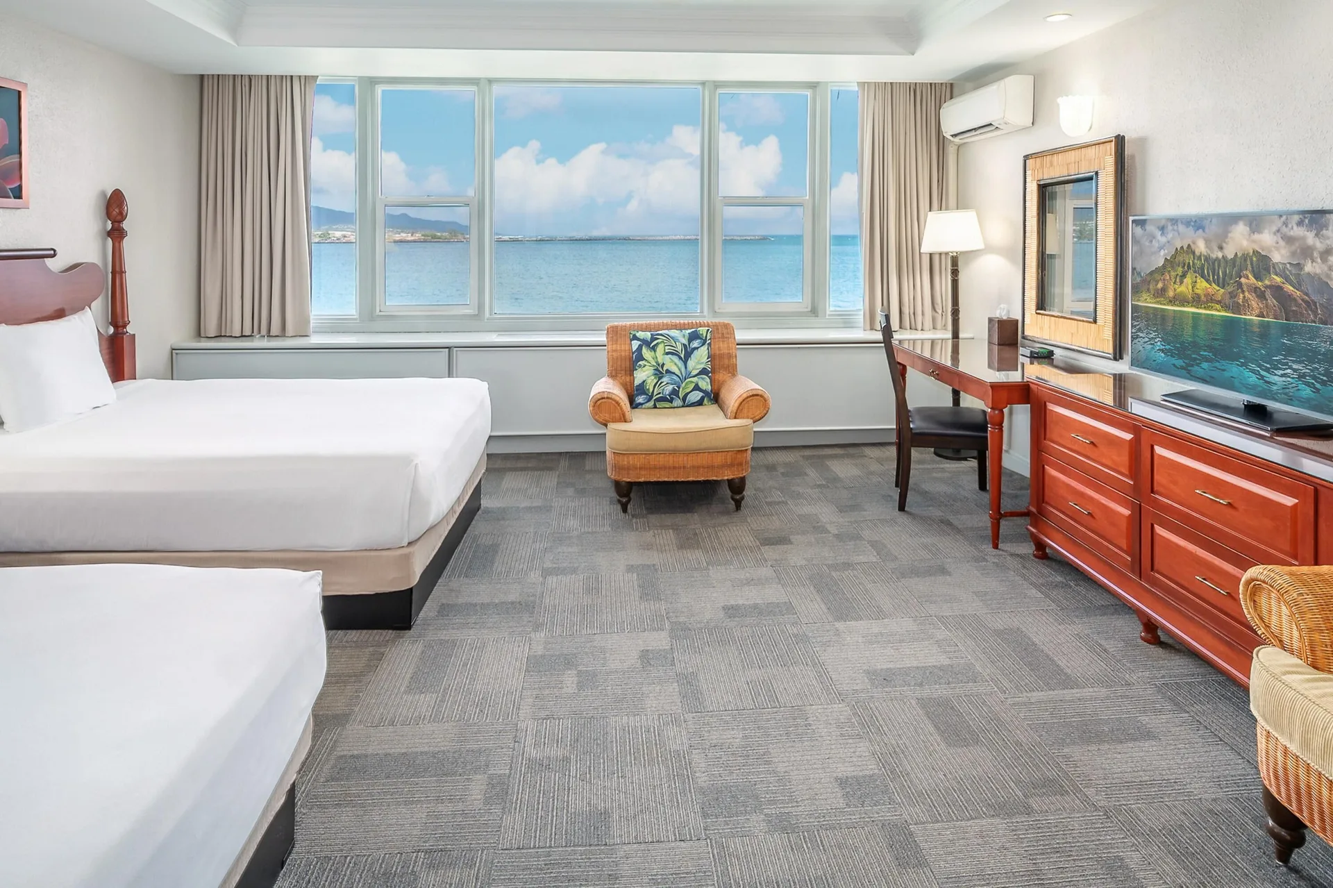Oceanfront suite with two beds, desk, TV, and sea view at Maui Beach Hotel.