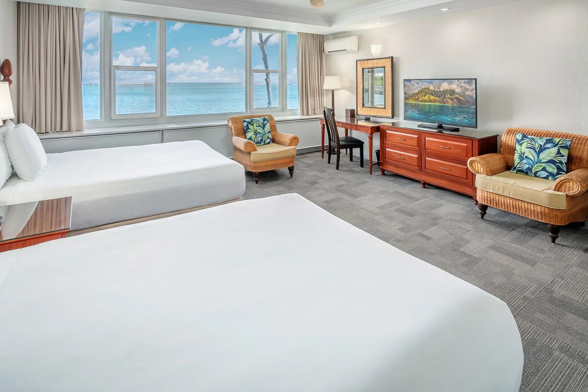 Oceanfront suite with two beds, chairs, and TV at Maui Beach Hotel.