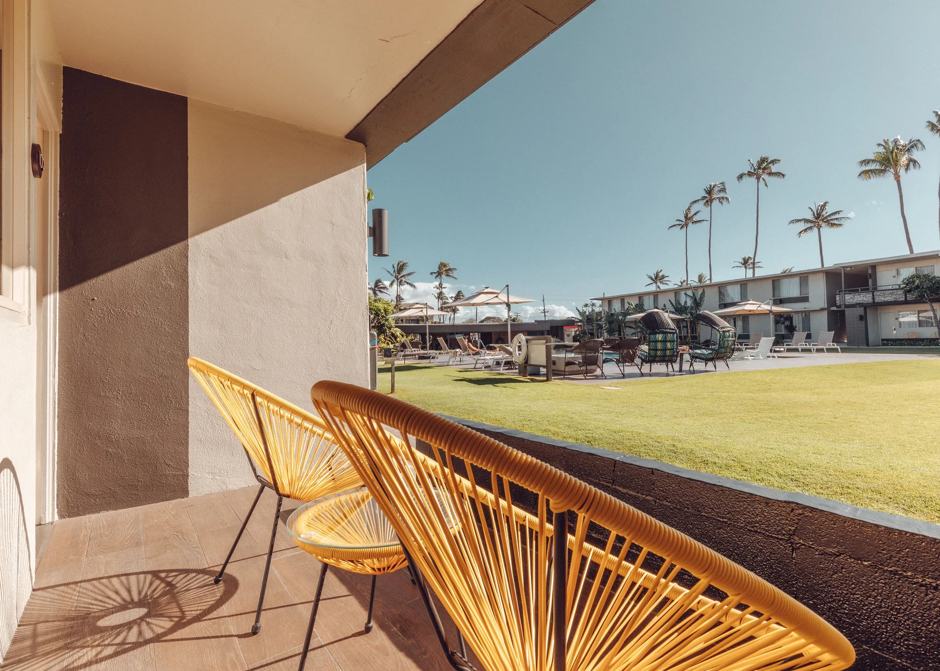 Yellow patio chairs overlook the lawn and pool area at Maui Seaside Hotel.