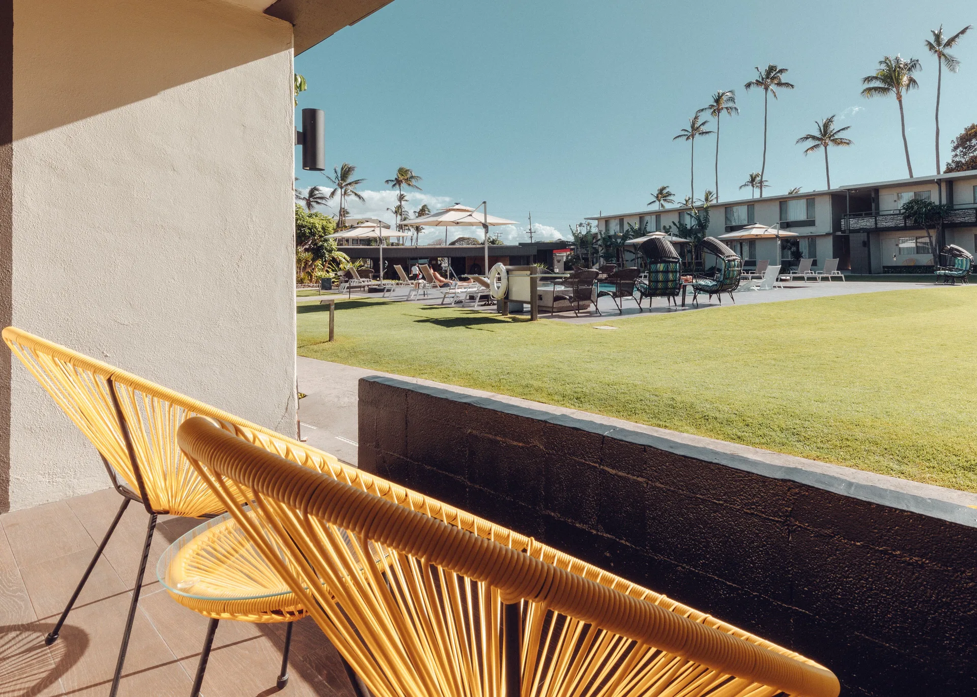 Yellow chairs on a shaded patio face the courtyard at Maui Seaside Hotel.