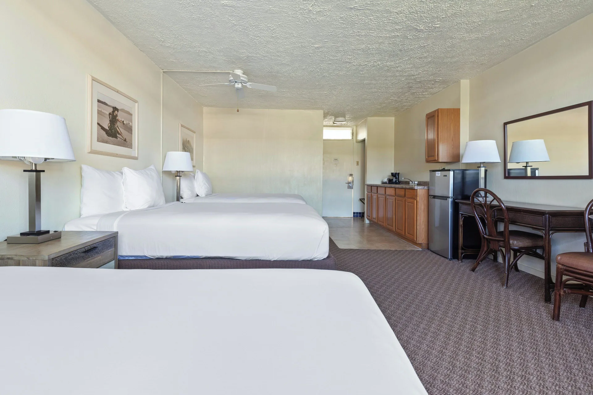 Poolside room with three beds, kitchenette, refrigerator, and dining table at Maui Seaside Hotel.