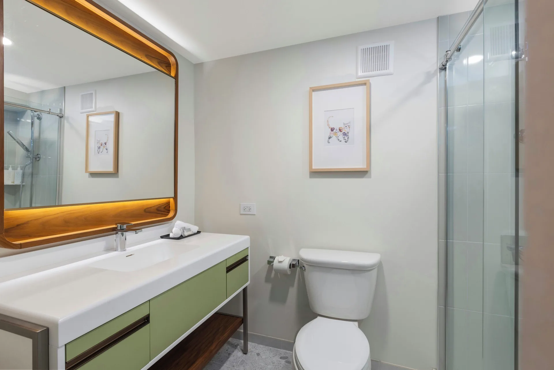 Renovated guest room bathroom with vanity and glass shower at Maui Seaside Hotel.