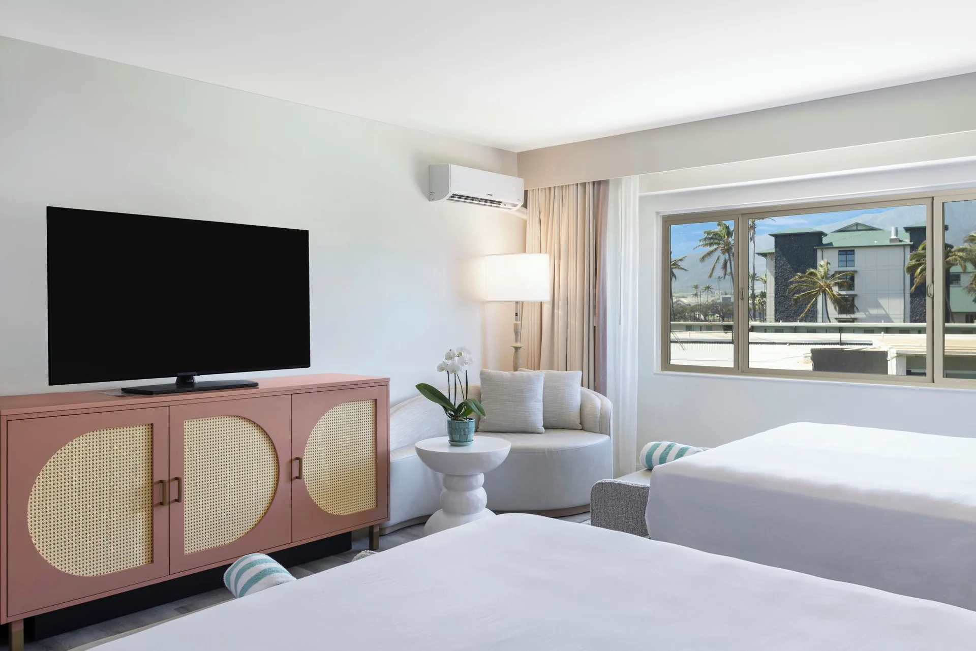 Renovated island view guest room with two beds and window at Maui Seaside Hotel.