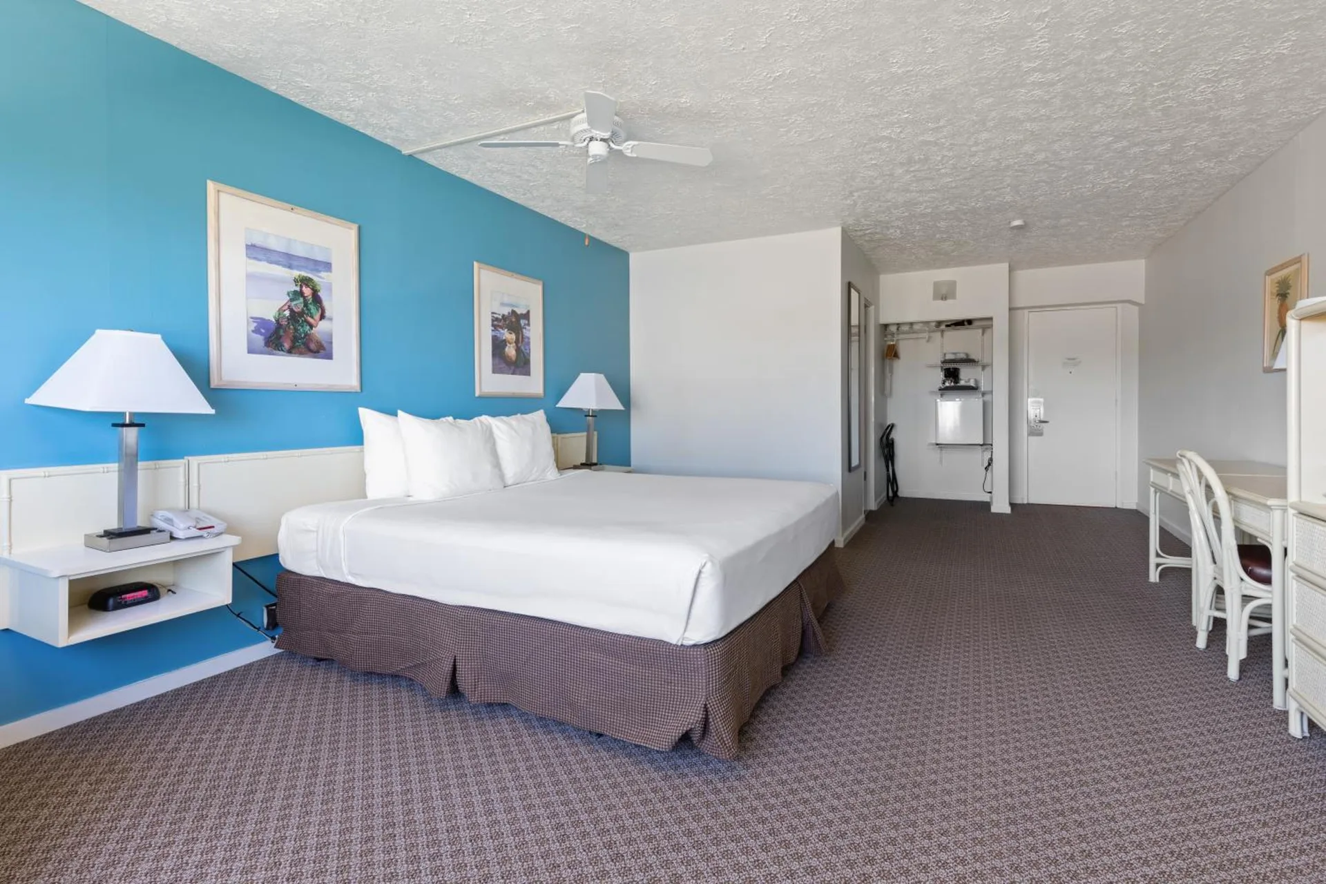 Standard One guest room with one bed, blue accent wall, desk and entry at Maui Seaside Hotel.