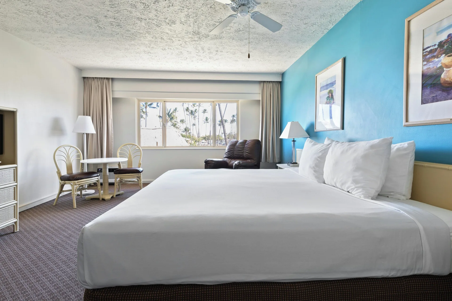 Standard Room with king bed, dining table and palm views at Maui Seaside Hotel.