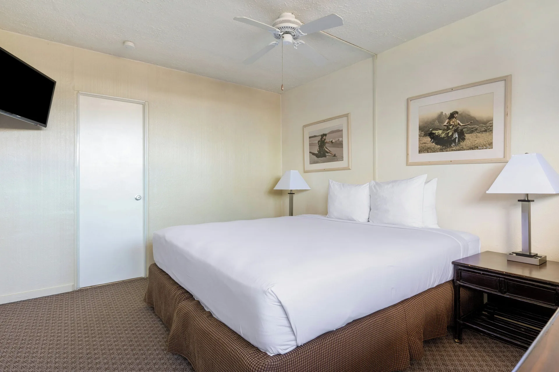 Standard Room with king bed, wall-mounted TV and ceiling fan at Maui Seaside Hotel.