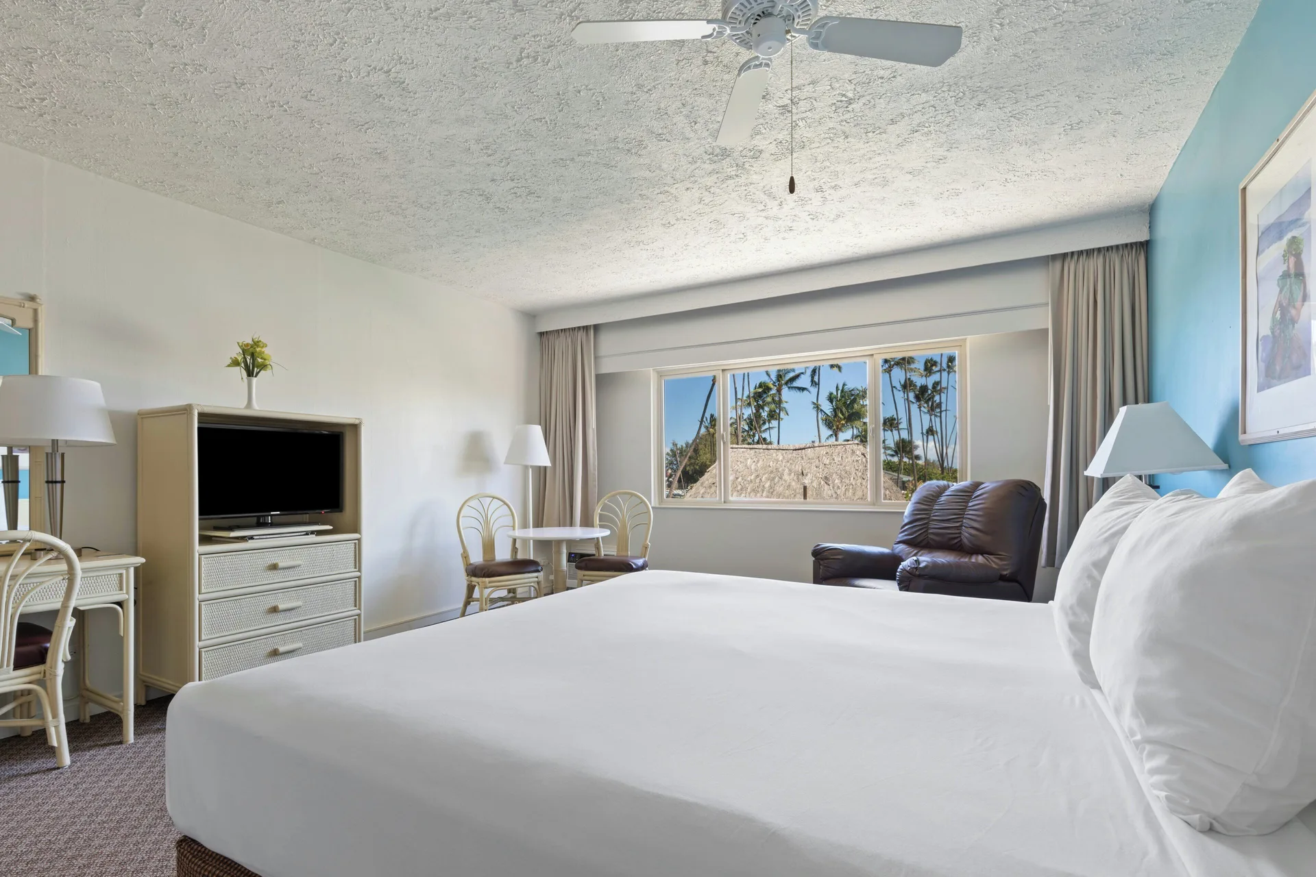 Standard Room king bed with seating, TV, and palm-view window at Maui Seaside Hotel.