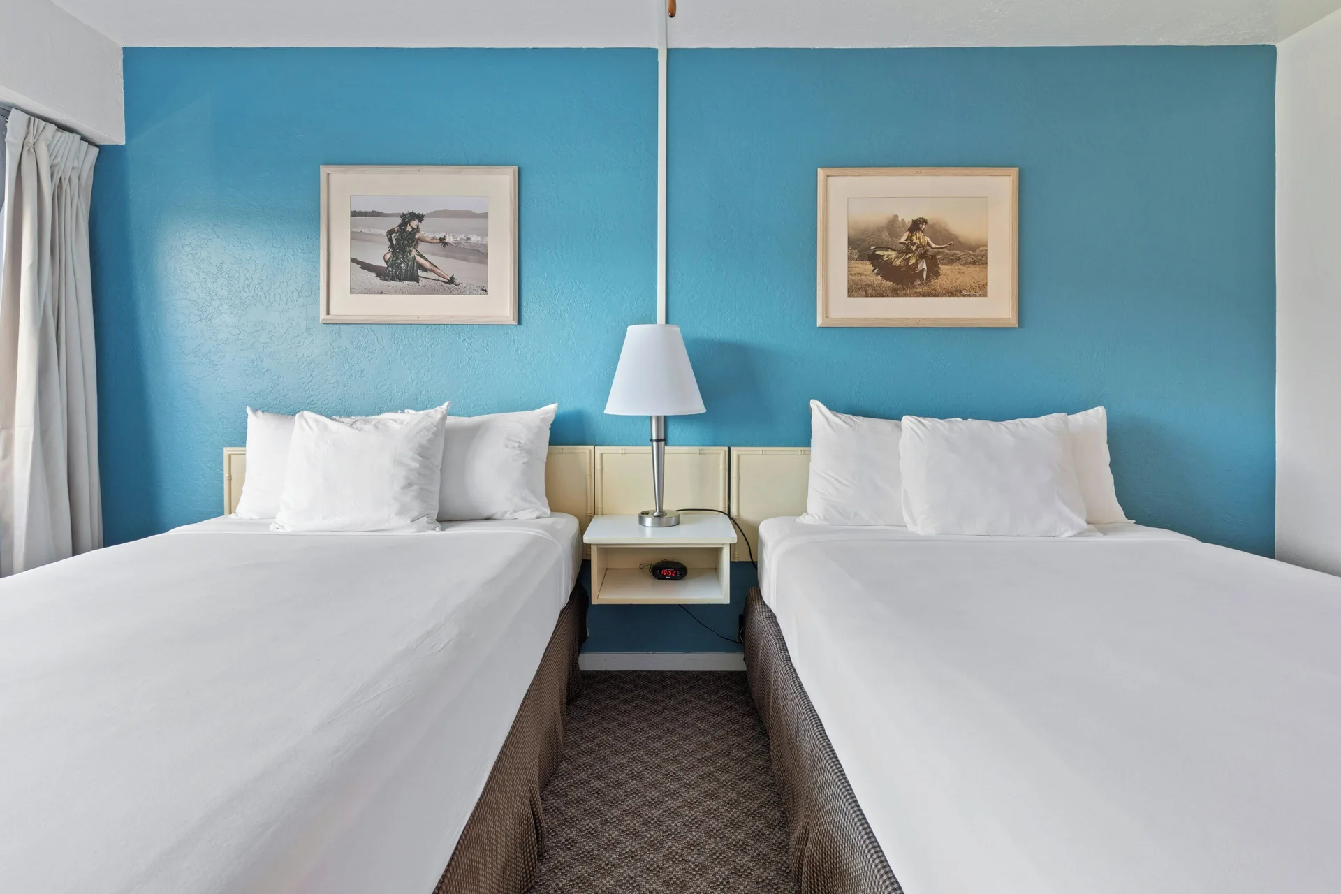 Standard Room with two beds, shared nightstand and blue wall at Maui Seaside Hotel.