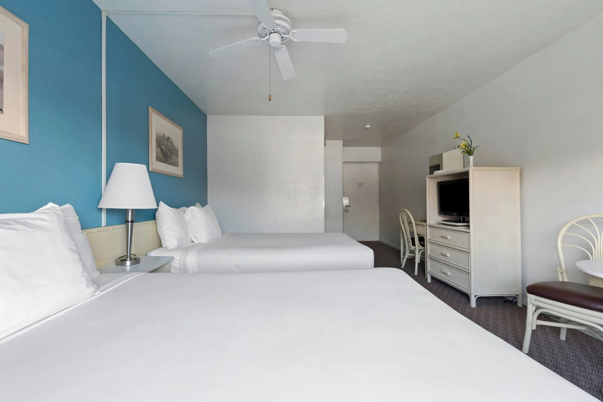 Standard Room with two beds, TV cabinet and blue accent wall at Maui Seaside Hotel.