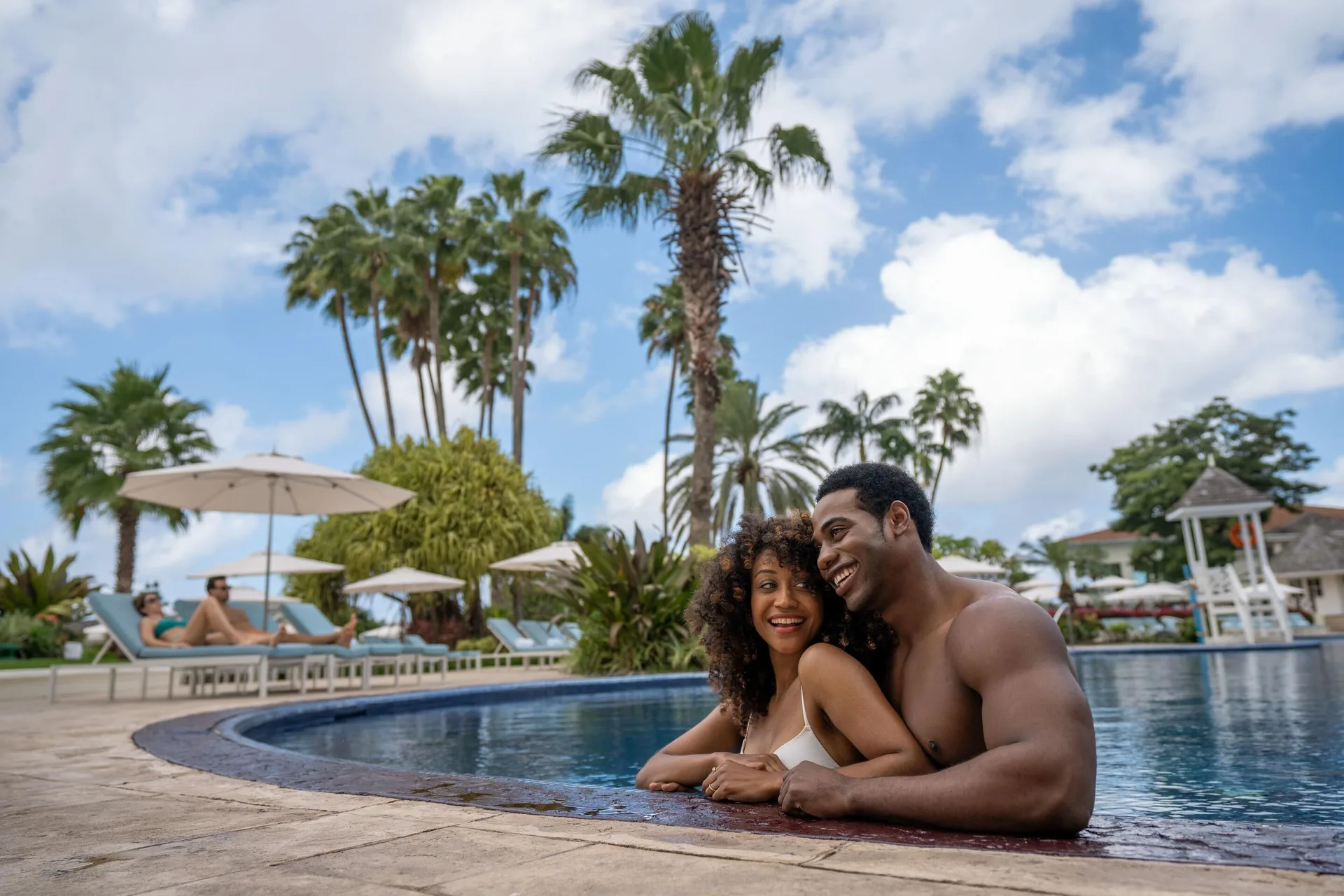 Couple relaxing at the edge of a palm-lined pool at Moon Palace Jamaica.