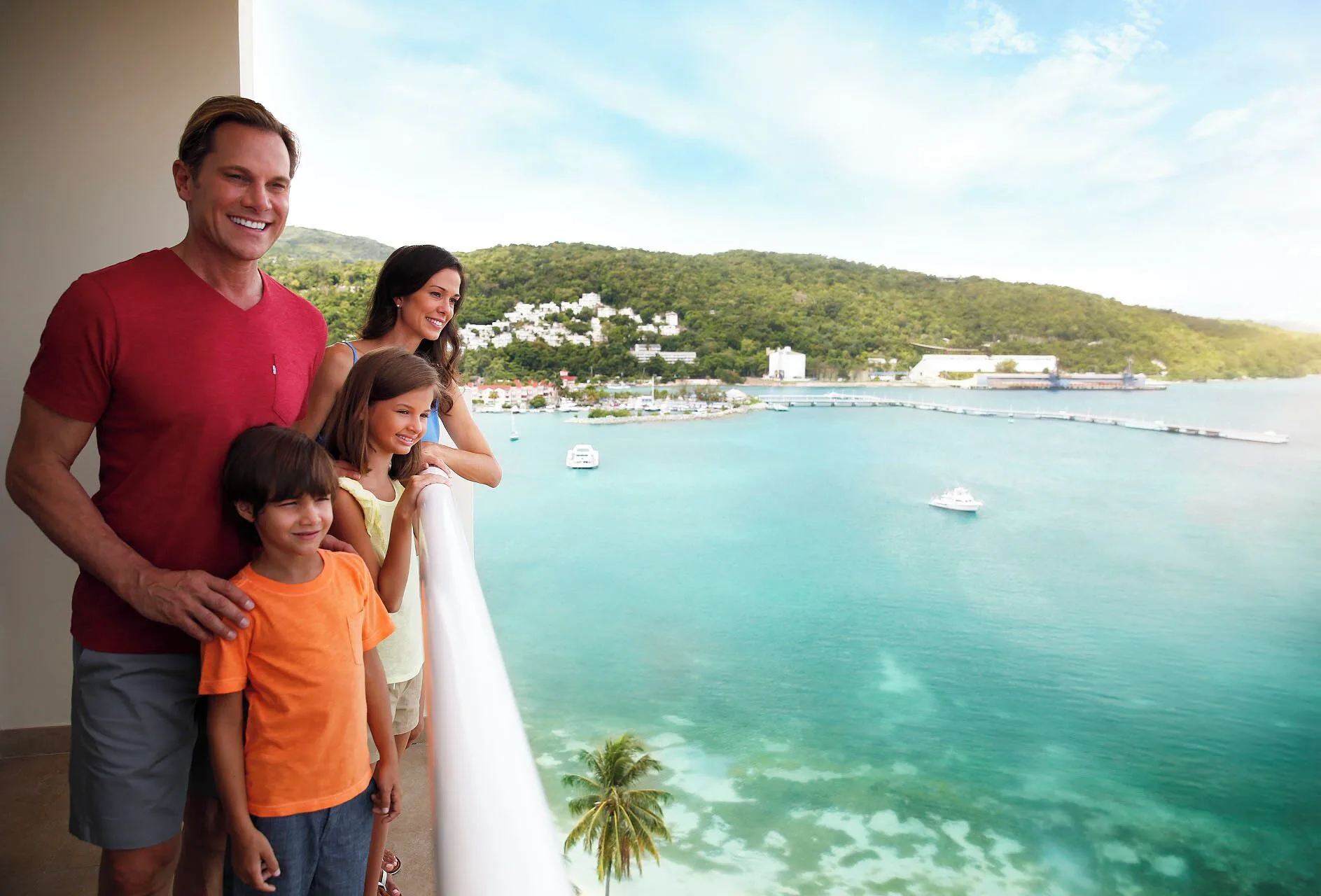 Family on a balcony overlooking turquoise water at Moon Palace Jamaica.