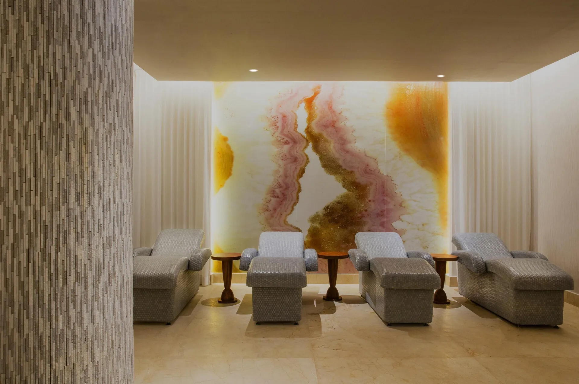 Spa relaxation lounge with cushioned chairs and abstract wall art at Moon Palace Jamaica.