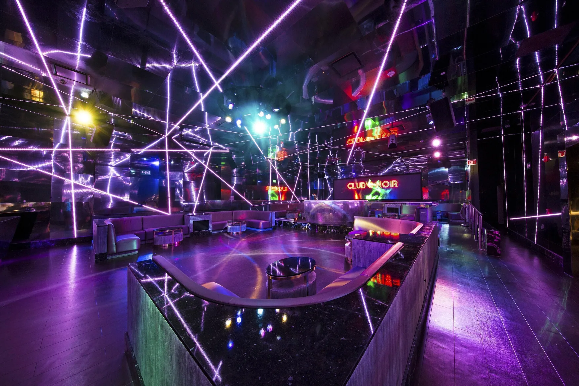 A nightclub dance floor with purple light beams and lounge seating at Moon Palace Jamaica.