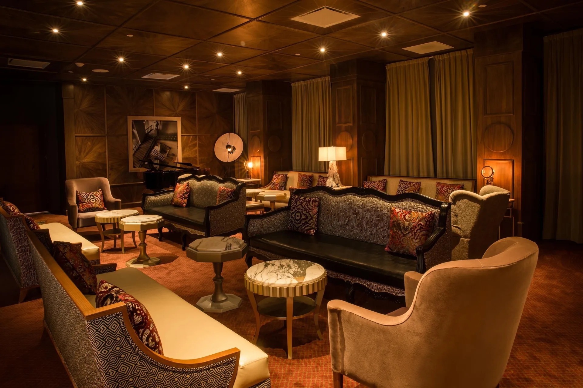 A warmly lit lounge with sofas, armchairs, and a piano at Moon Palace Jamaica.