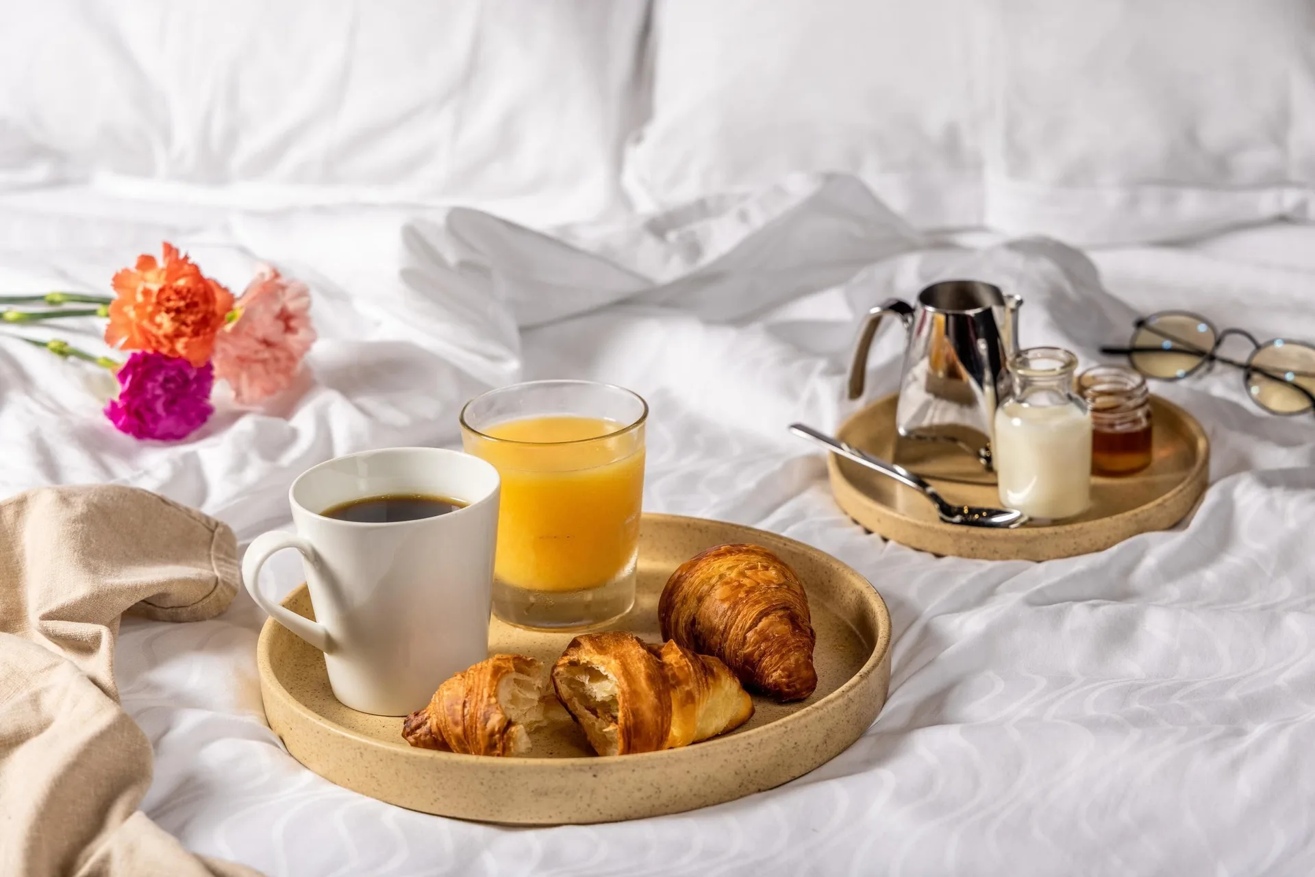 Breakfast trays on white bedding in a guest room at Moon Palace Jamaica.