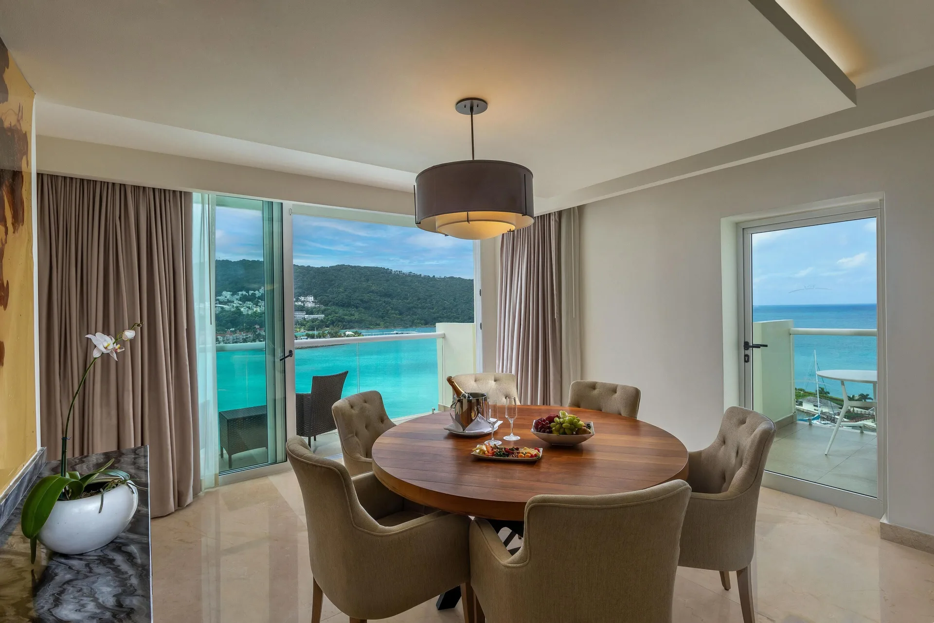 Round dining table beside ocean-view balcony doors at Moon Palace Jamaica.