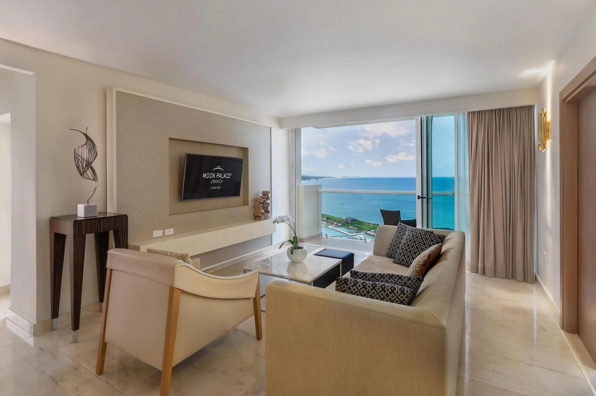 Ocean-view living room with sofa and TV at Moon Palace Jamaica.