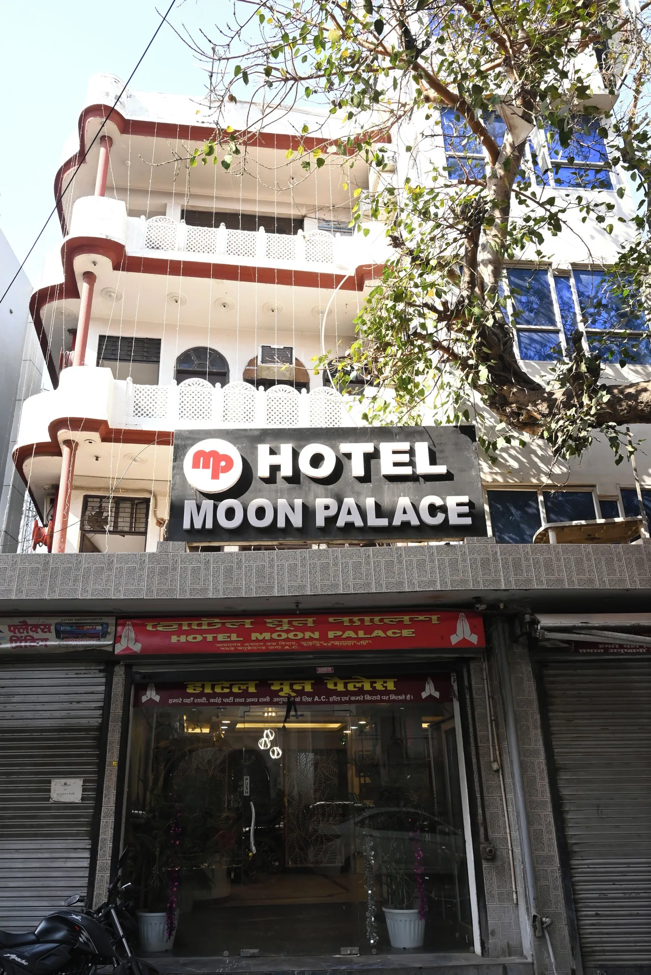 The Moon Palace street entrance with a large hotel sign below balconies and a tree.