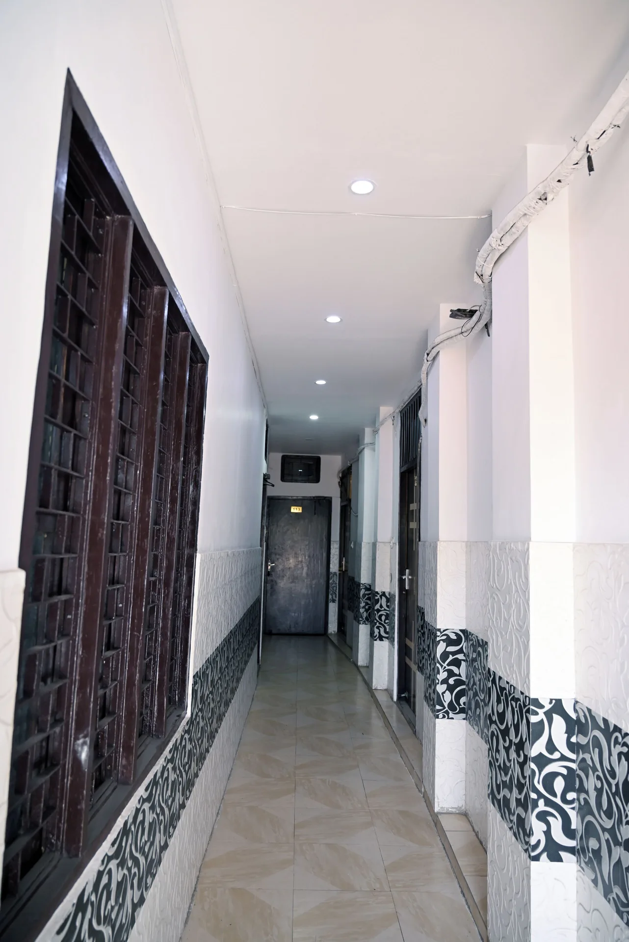 A narrow tiled guest corridor with dark windows and doors at Moon Palace.