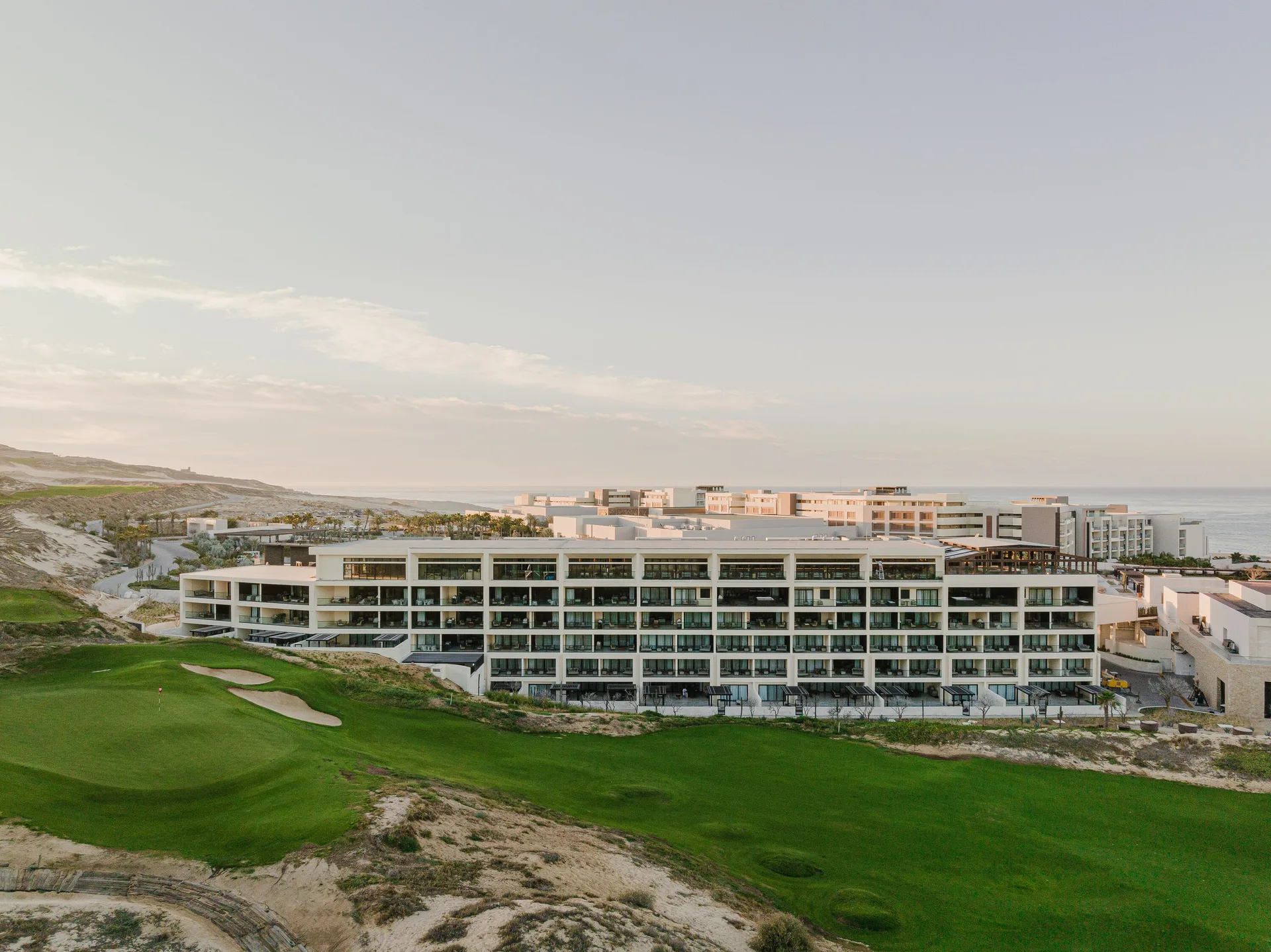 Aerial view of resort buildings, golf greens and coastline at Nobu Hotel Los Cabos.