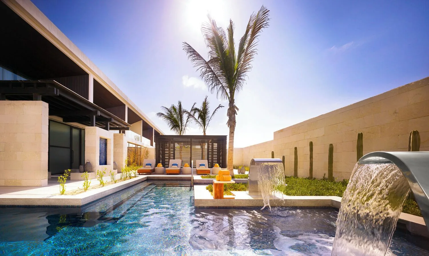 An outdoor spa pool with waterfall spouts and loungers at Nobu Hotel Los Cabos.