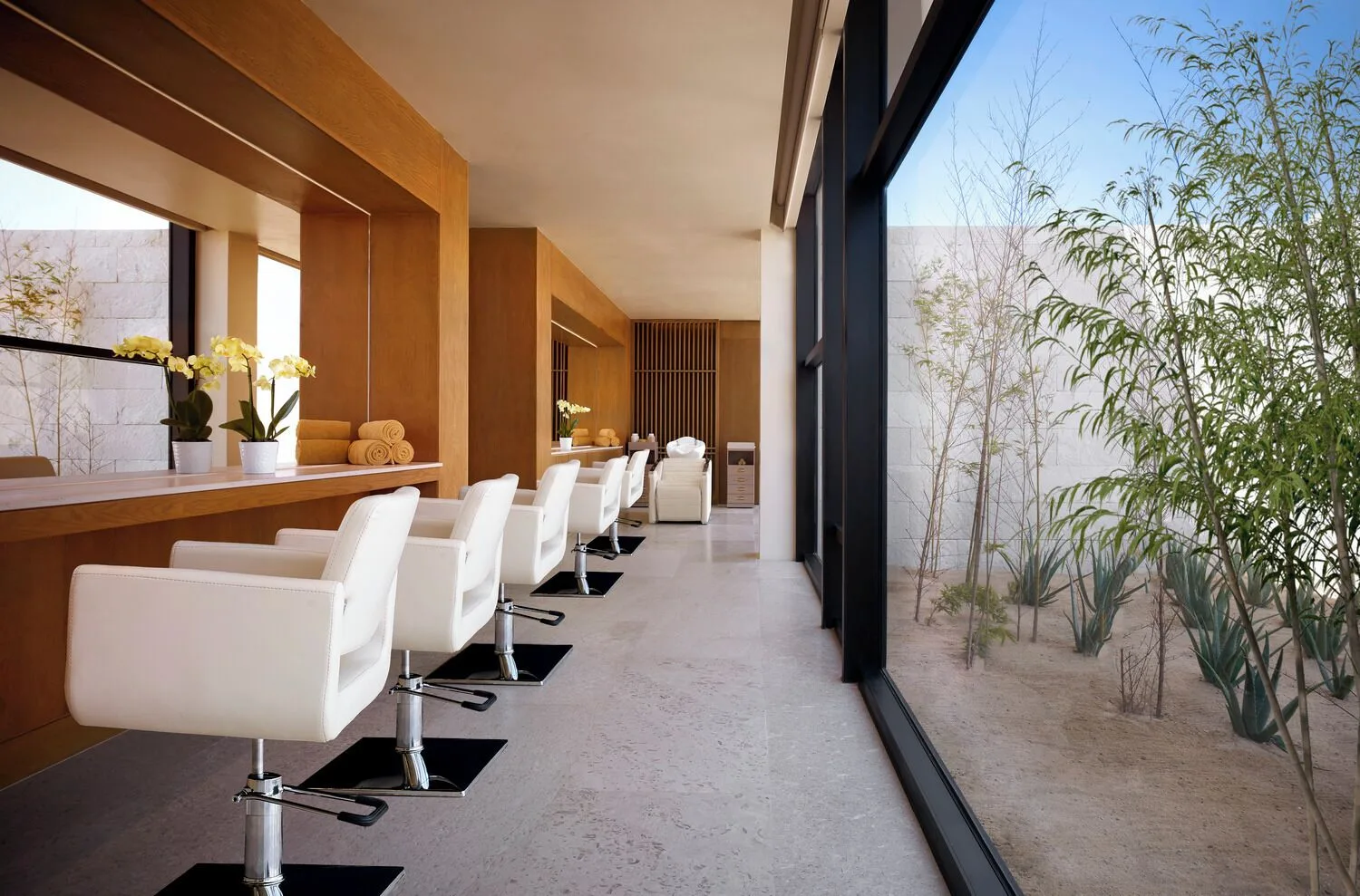 A salon area with white styling chairs and desert garden views at Nobu Hotel Los Cabos.