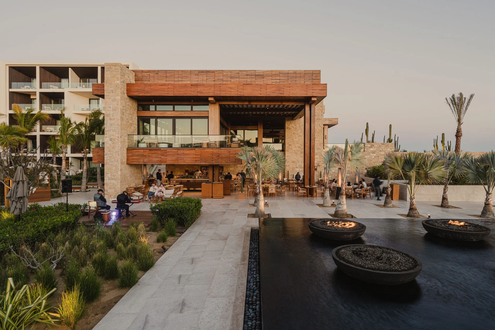 Evening restaurant terrace with fire bowls and desert landscaping at Nobu Hotel Los Cabos.