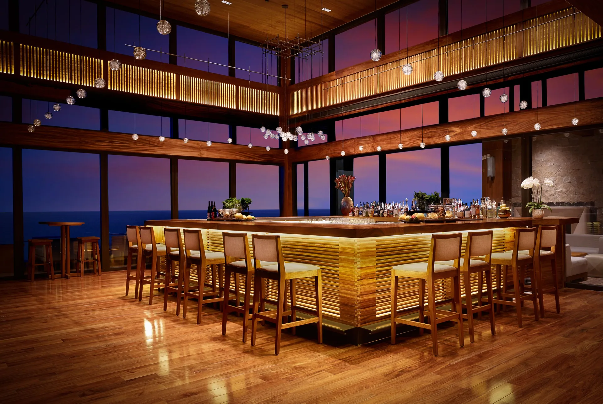 Ocean-view bar with sunset windows and warm wood interiors at Nobu Hotel Los Cabos.