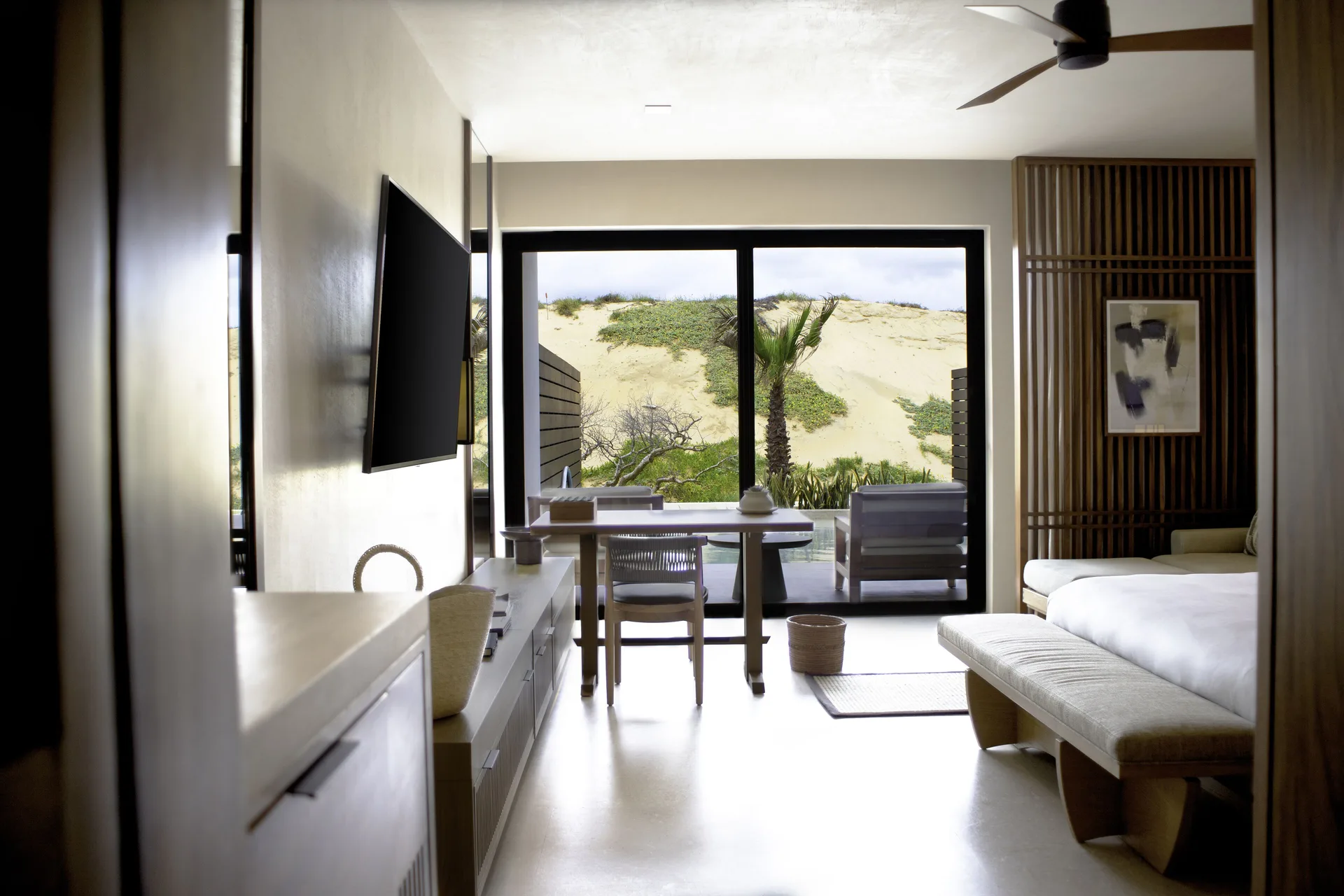 Deluxe Swim-Up Room with bed, desk, TV, and dune-facing glass doors at Nobu Hotel Los Cabos.