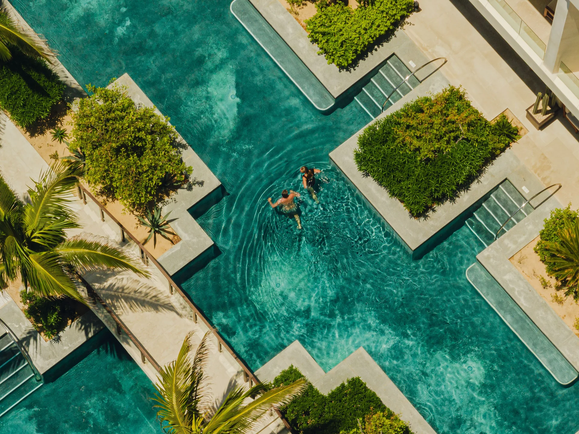 Swim-up pool area with guests in the water by Deluxe Rooms at Nobu Hotel Los Cabos.